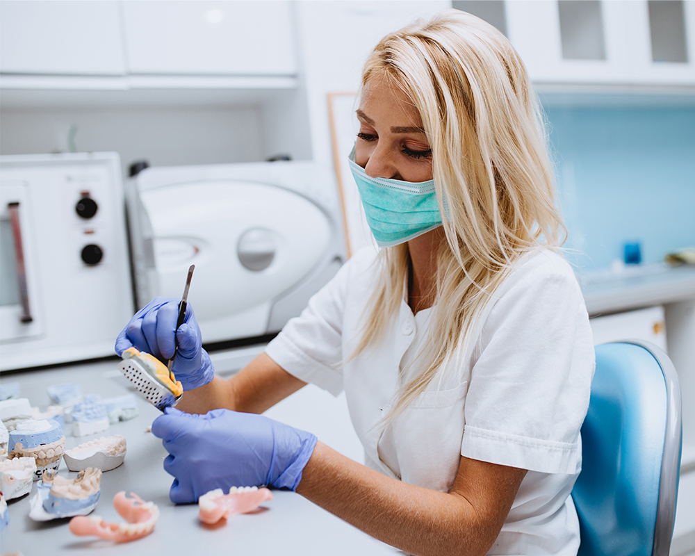 Zahntechnikerin bei der fertigung eines Zahnersatzes